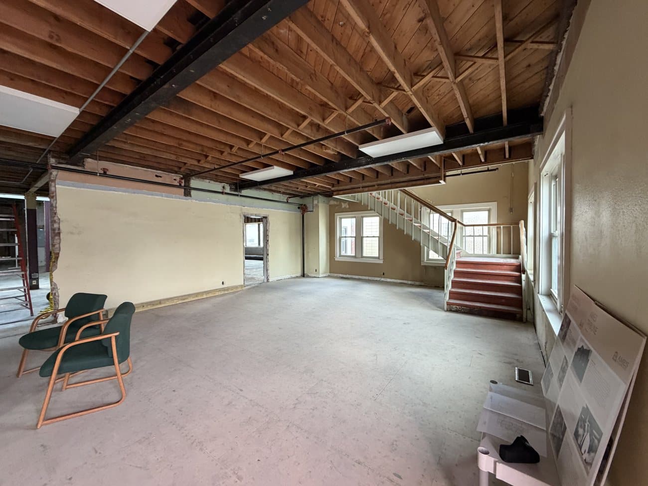 An upper-floor room with the staircase and downtown windows
